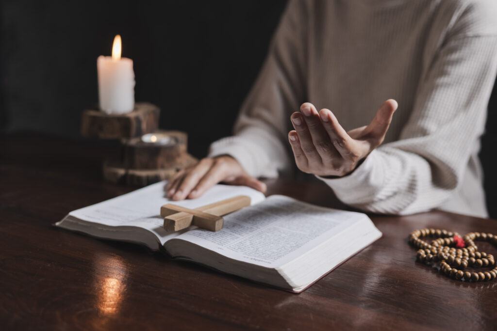 Woman praying with the bible on the table. The hand of a Christian woman rests on the Bible to pray for God.